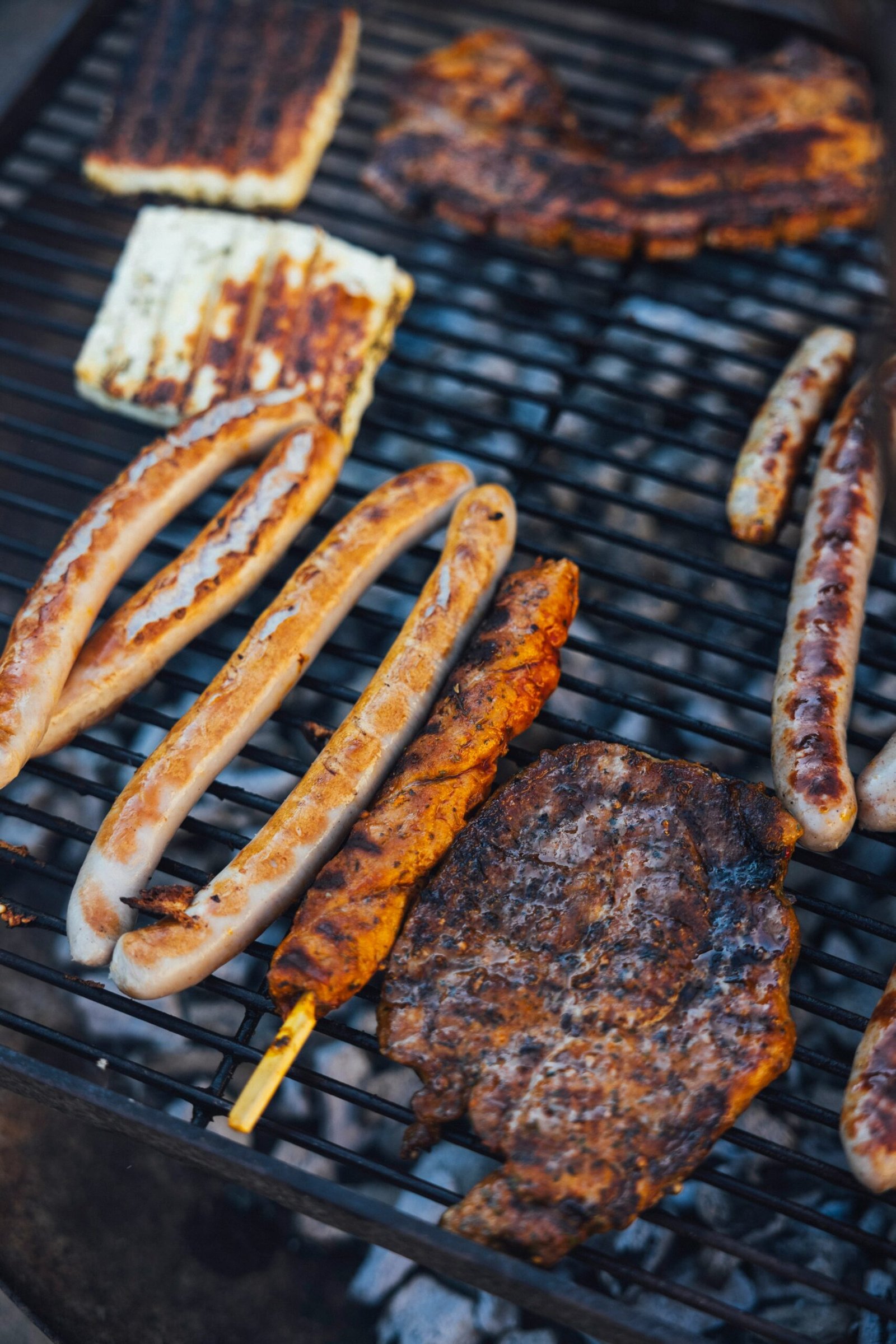 a grill with several sausages and hot dogs cooking on it